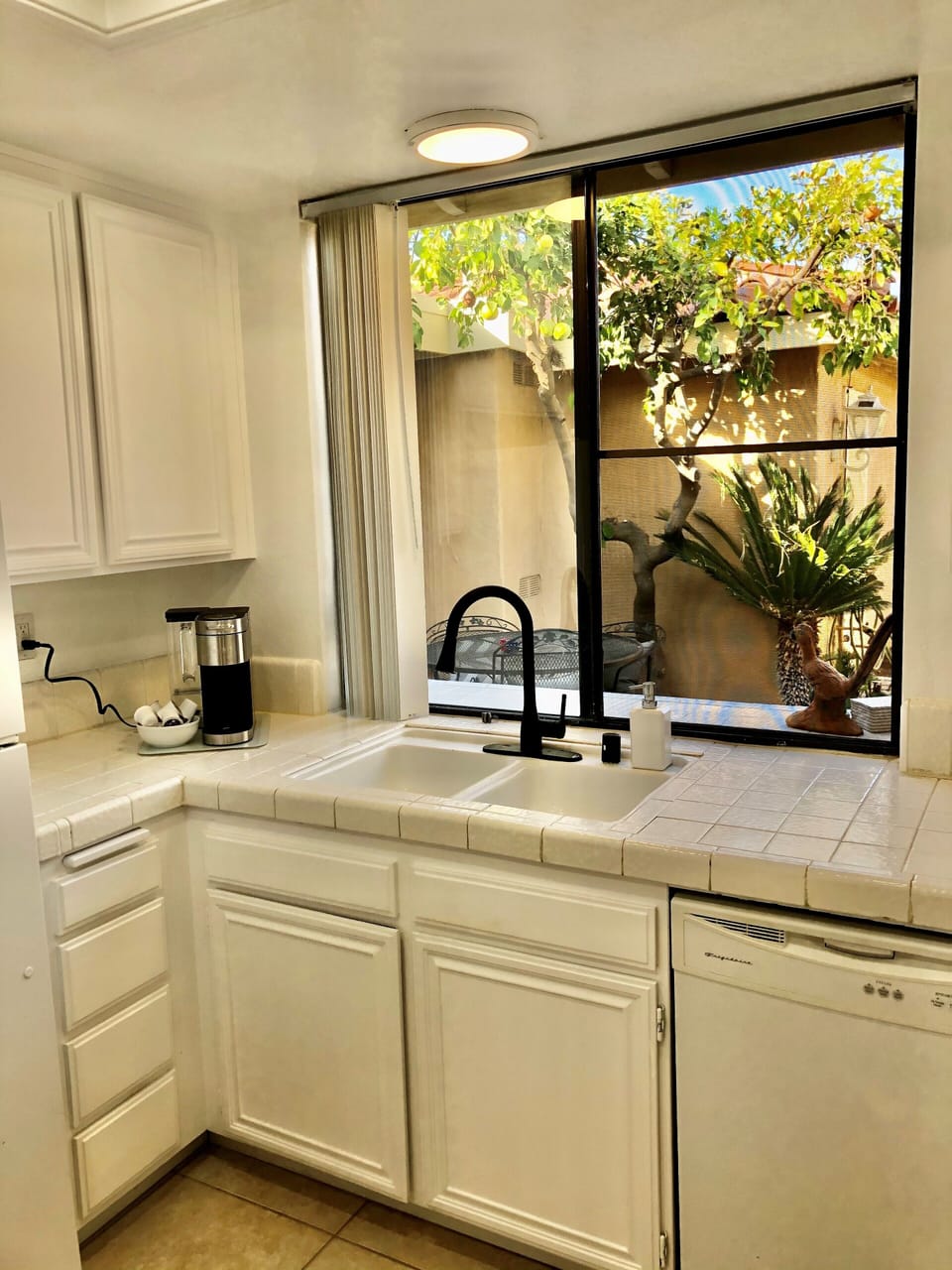 Kitchen sink with view of private entrance and patio.