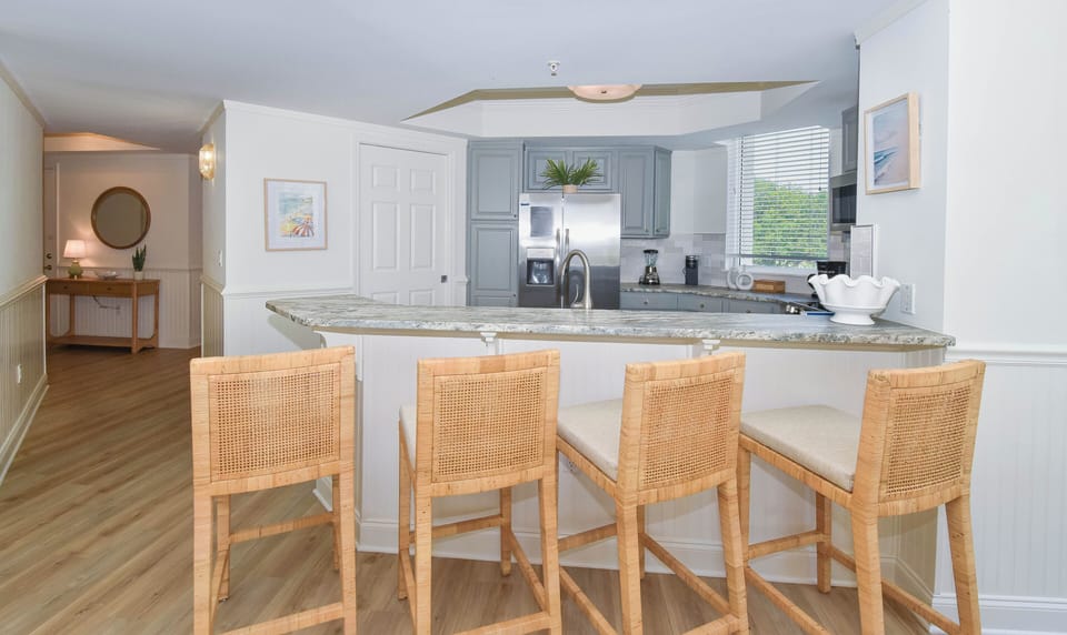 Gather around this open kitchen island with bar seating for four, featuring granite countertops, stainless appliances, and coastal-inspired décor—perfect for your morning coffee or evening conversations.