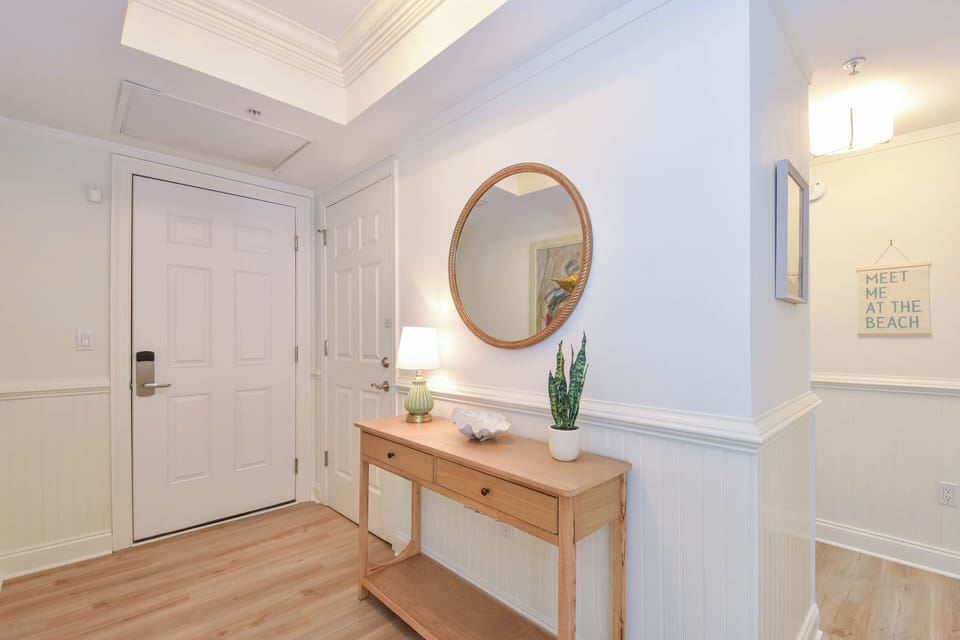 Step through your private entrance into a bright, welcoming foyer with coastal charm. A warm wooden console and beach-inspired artwork set the tone for your relaxing getaway.