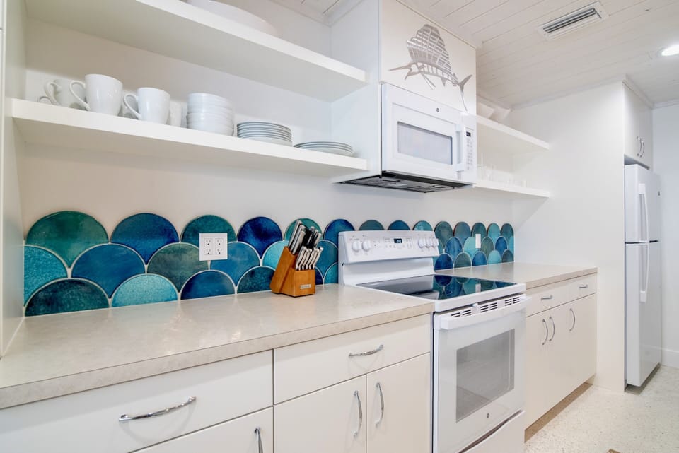 Watercolored handmade, hand glazed terra cotta tiles are the focal point of this fully stocked cottage kitchen.