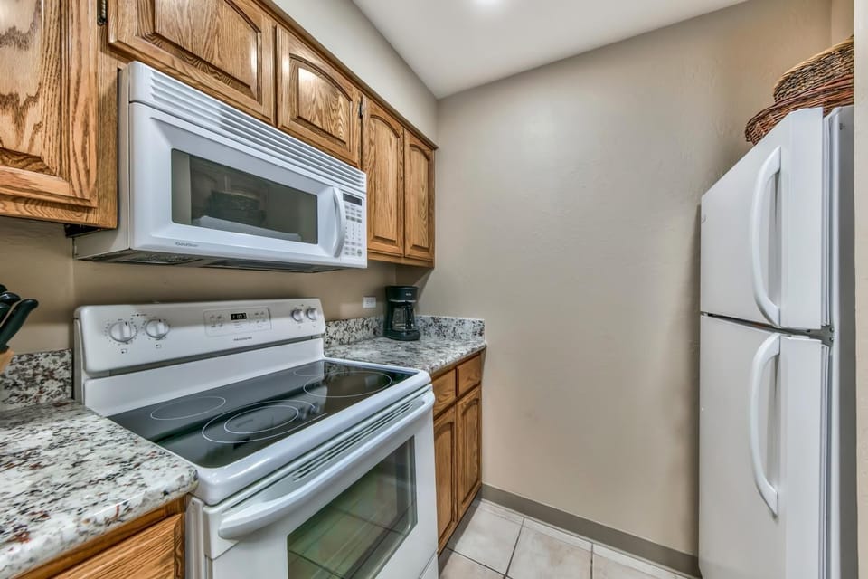 The kitchen is complete with an oven, electric stove, microwave, fridge/freezer, dishwasher, and additional small appliances