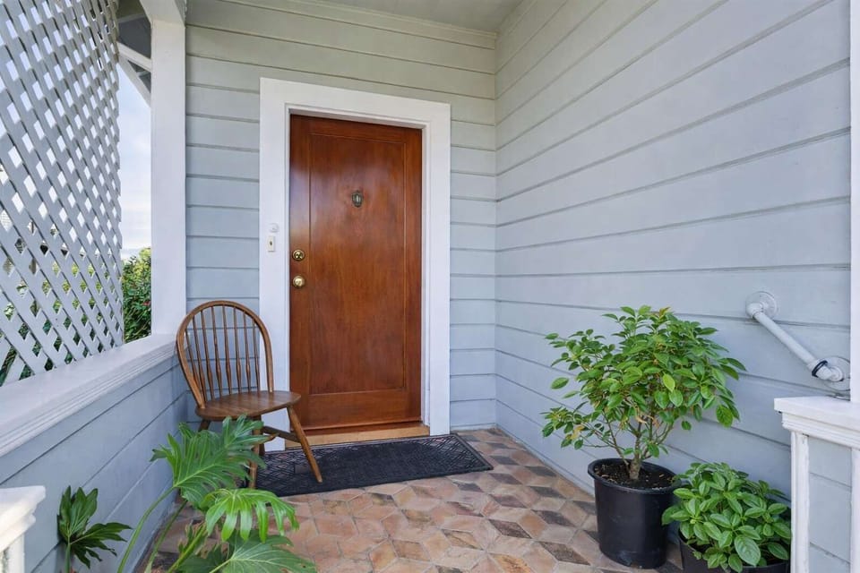 Private, covered entry with seating, greenery, and a welcoming front door—charming first impression and a quiet spot to enjoy fresh air.
