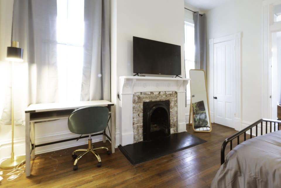 The Magnolia Room is a private bedroom with queen bed, mirror, TV and desk.