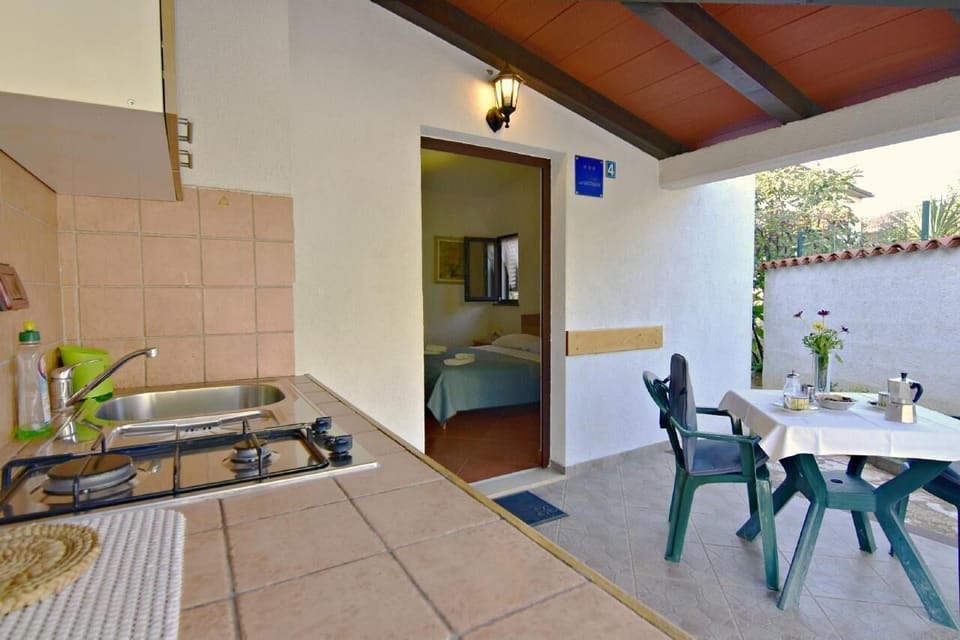 The covered terrace with an equipped kitchen and table with 4 chairs, the entrance to the apartment.