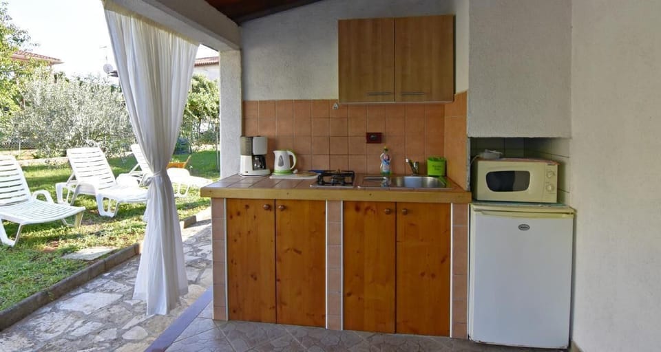 The outdoor kitchen with fridge, microwave, two-burner gas stove, kettle, and coffee maker.