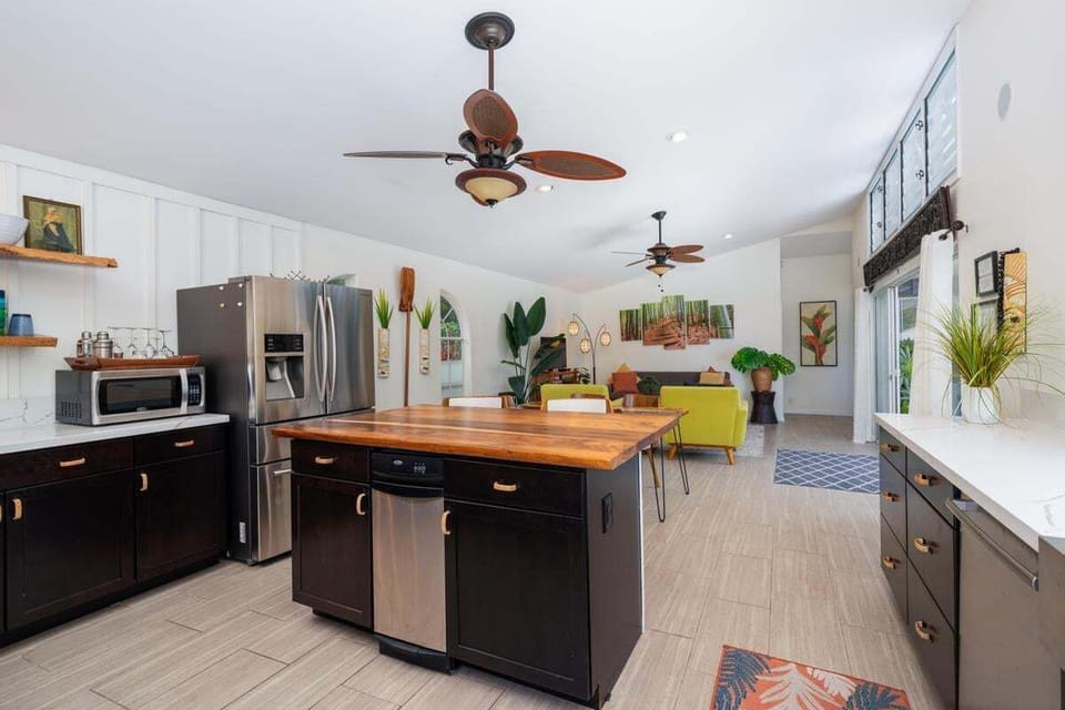 A beautifully designed kitchen with natural wood countertops, large island, high-back stools, and quality appliances.