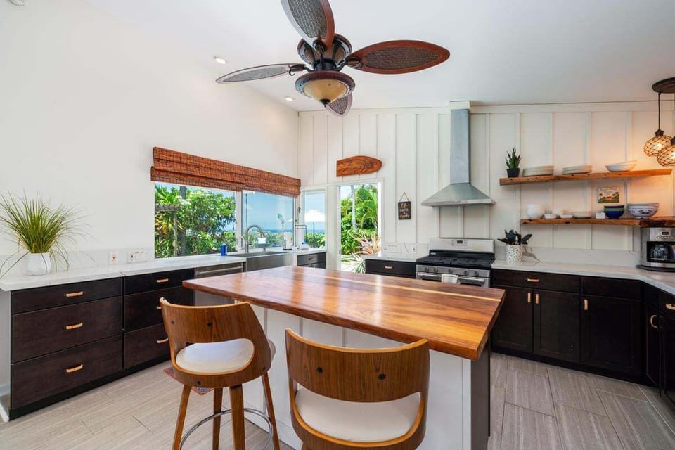 A beautifully designed kitchen with natural wood countertops, large island, high-back stools, and quality appliances.