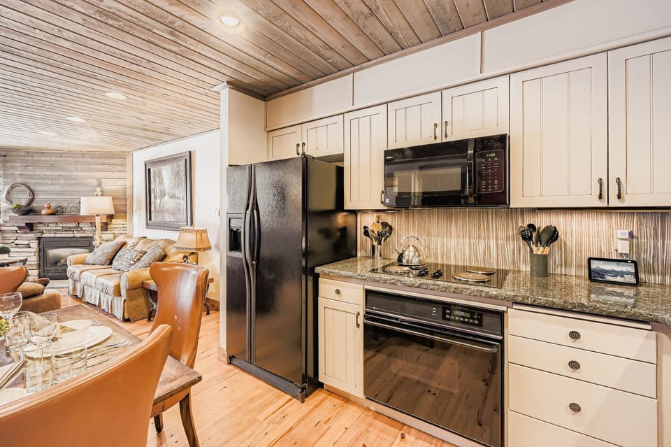 Your fully-equipped kitchen features stainless steel appliances, granite countertops, and rustic wood beam ceilings that create a warm, inviting space for cooking.