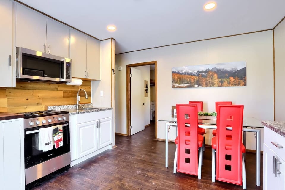 - Fully equipped kitchen with microwave, gas stove, & warm wood accents
- Dine with a view under ambient lighting while enjoying panoramic artwork of golden autumn trees
- Seamless layout connects kitchen and dining with inviting energy and comfort
