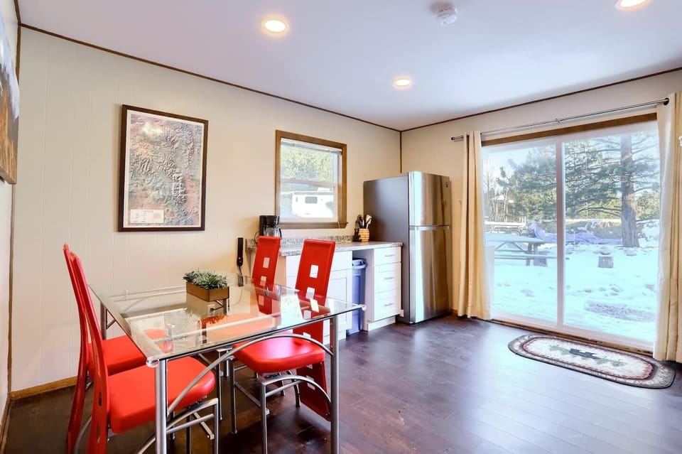 - Dine indoors with scenic outdoor views through glass doors that open to nature
- Clean modern lines meet rustic vibes with red chairs and wood style flooring
- Enjoy meals or morning coffee while soaking in the peaceful snowy backdrop