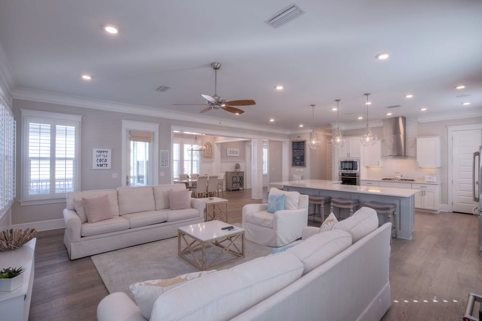 Open-concept living room featuring white sofas and soft coastal decor.