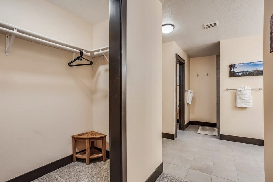 Your spacious walk-in closet features thoughtful storage with hanging rods and a charming wooden stool for easy organization.