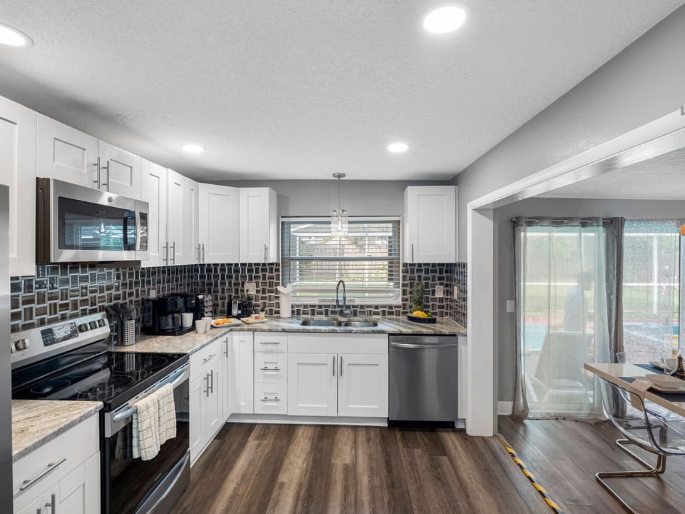 This fully equipped kitchen features modern stainless steel appliances, spacious countertops, and a sleek tile backsplash—perfect for preparing anything from a morning coffee to a gourmet meal.