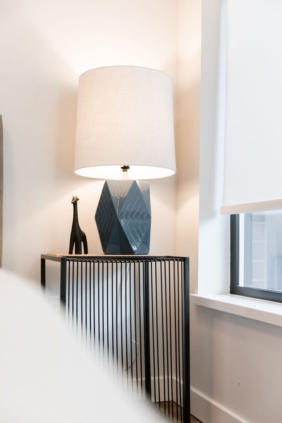 Nestle into the fresh, white linens and soft pillows of this cozy bed. A charming giraffe decor piece adds character to the nightstand, while natural light brightens the room, keeping things peaceful yet playful.