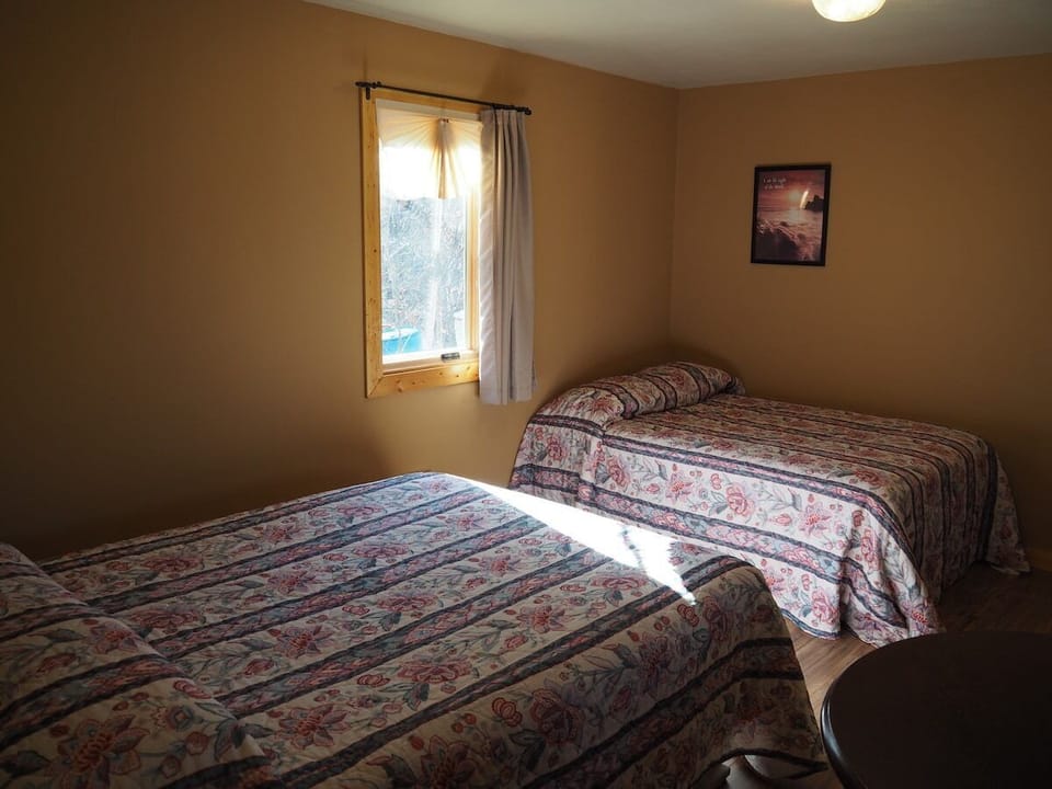MAIN ROOM:  Features two double beds, small dining table with chairs, and a sink / kitchenette.