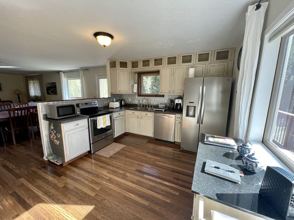 Fully stocked kitchen with many appliances, spices, plate ware and glass ware. 