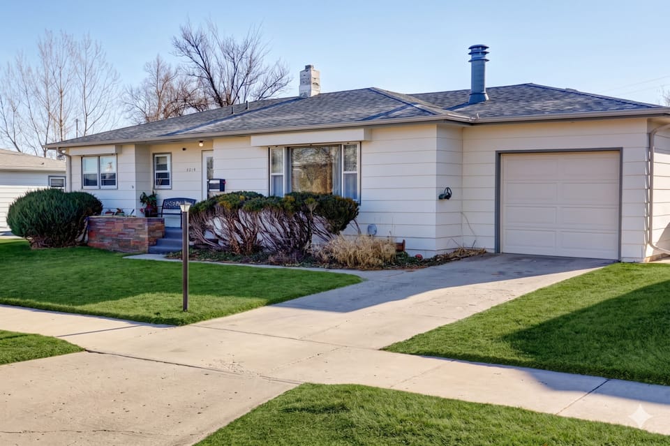 Home exterior with attached garage, manicured landscaping, and stone steps