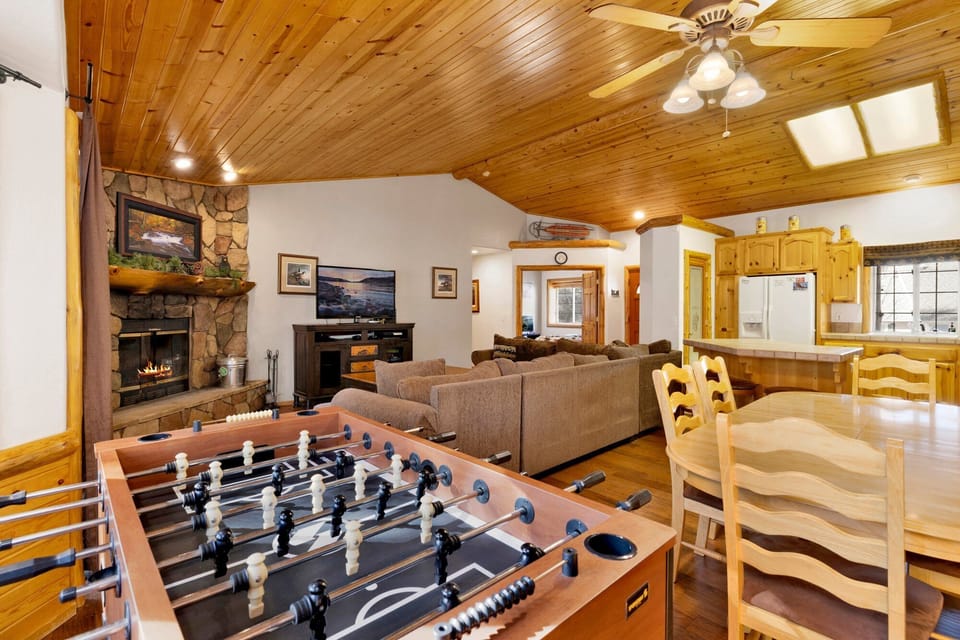 Cozy mountain living room with a stone fireplace, comfy seating, and smart TV—perfect for relaxing evenings, movie nights, and warm cabin vibes after outdoor adventures.
