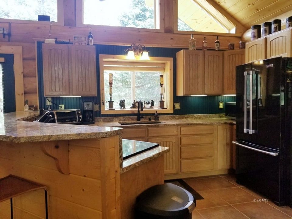 Double sink, microwave, toaster, side-by-side refrigerator and view to the back