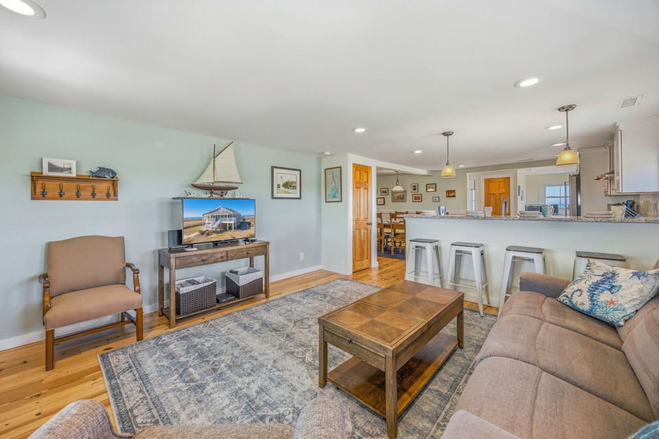 Relax in your open-concept living space with coastal charm, featuring comfortable seating and a full kitchen for memorable gatherings.