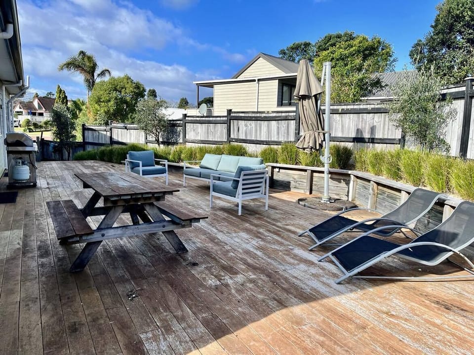 Rear deck with BBQ, picnic table, sun loungers & outdoor couches.