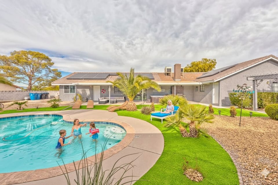 This expansive backyard offers a perfect retreat with a sparkling swimming pool, lush artificial turf, and desert landscaping. Relax on comfortable loungers, or splash in the pool. A true oasis for enjoying the Las Vegas sun.