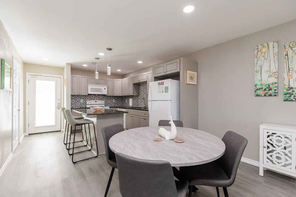 Your open-concept kitchen and dining space invites memorable meals with modern gray cabinetry, stylish pendant lighting, and a welcoming round table.
