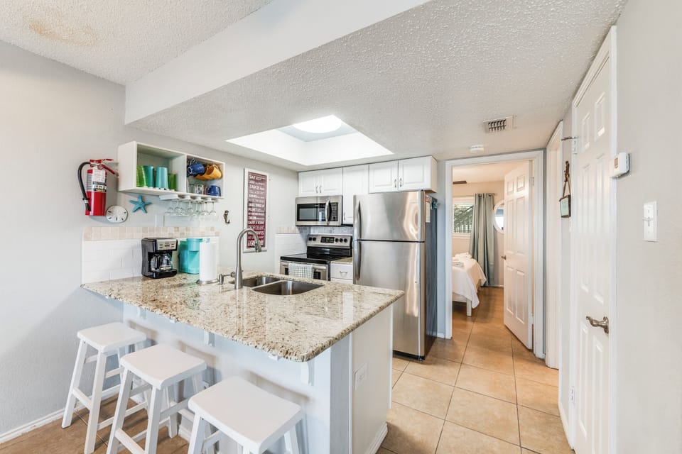 Your bright, fully-equipped kitchen features granite counters, stainless appliances, and a breakfast bar perfect for morning coffee.