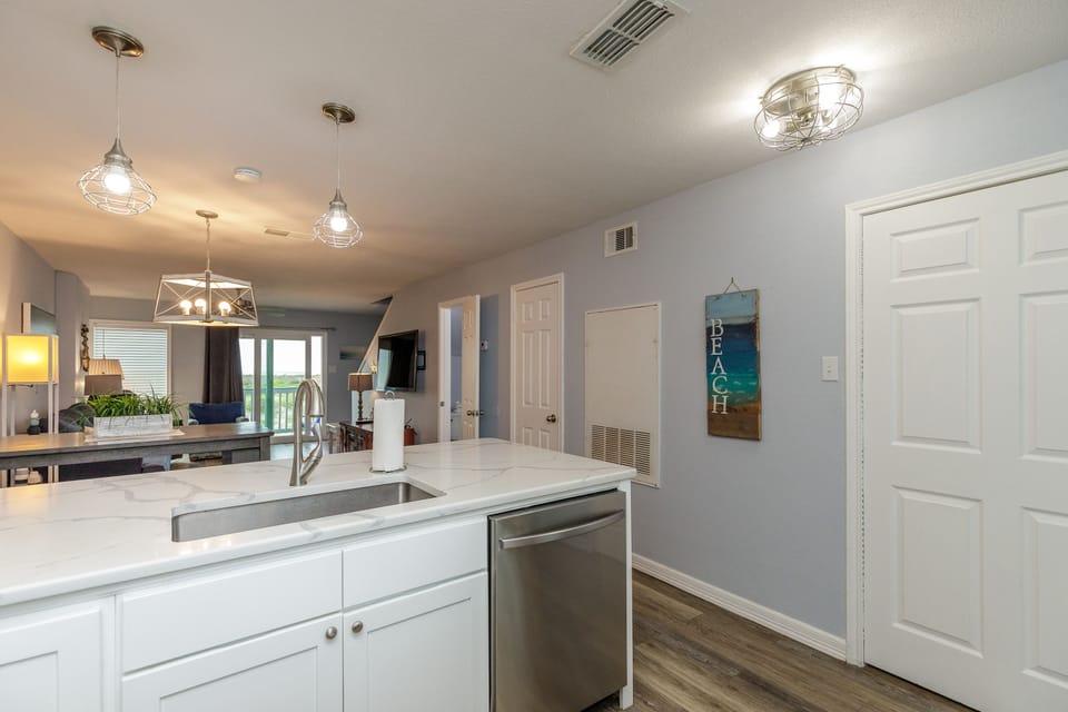 Your sleek kitchen features pristine white counters, stainless appliances, and warm pendant lighting for memorable meal prep.