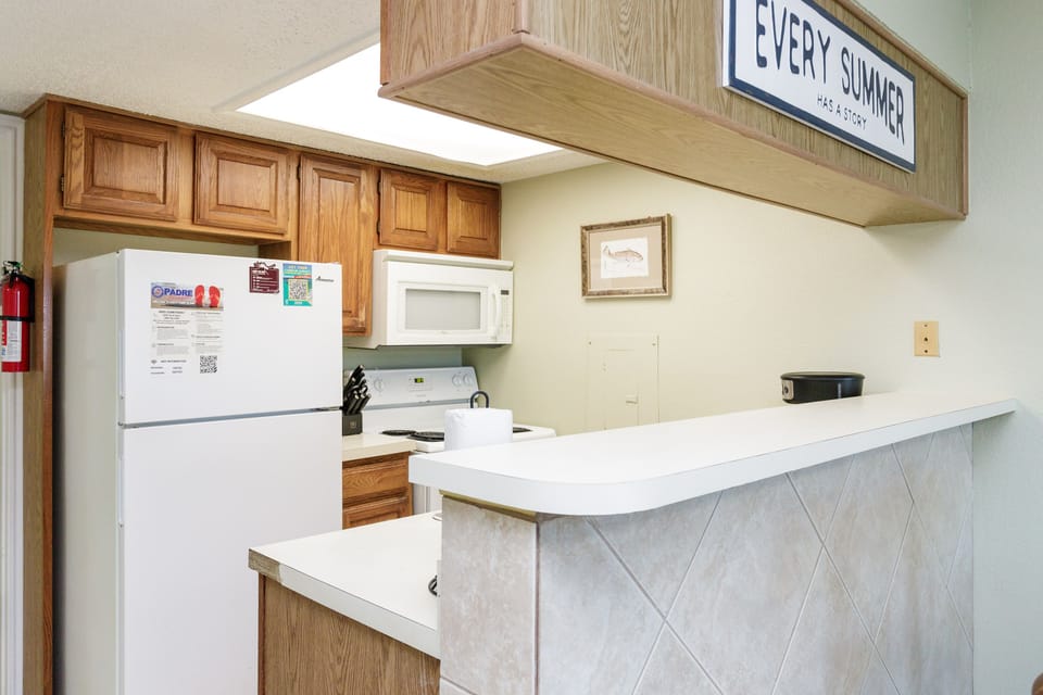 Your fully equipped kitchen features warm wood cabinets, modern appliances, and a bright breakfast bar perfect for casual meals.