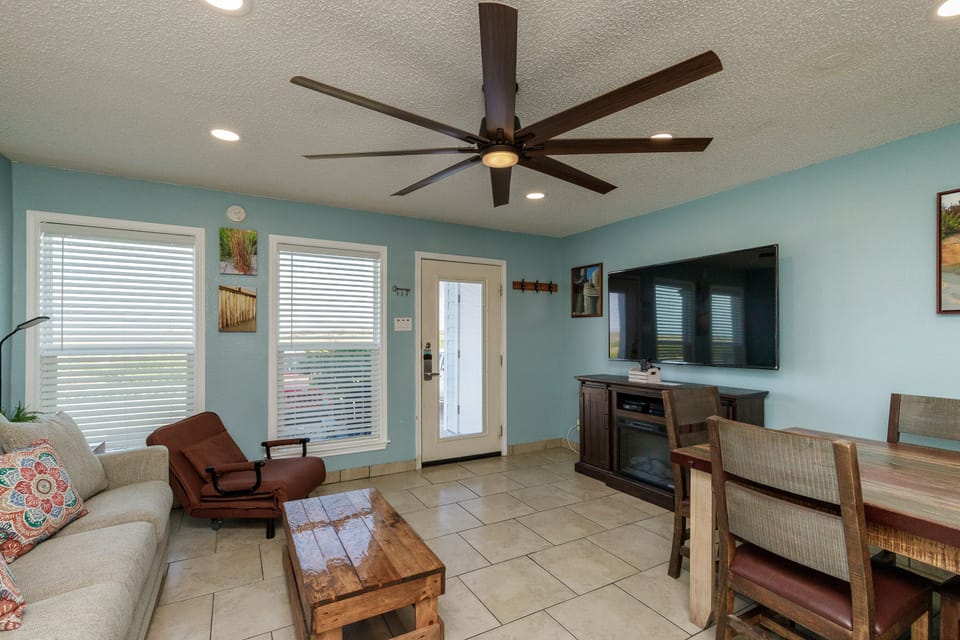Relax in your bright, coastal-inspired living space with comfortable seating, entertainment center, and soothing turquoise walls that create the perfect beach getaway atmosphere.