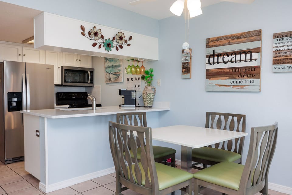 Your open kitchen flows seamlessly into the bright dining area, where coastal-inspired decor and cheerful touches create the perfect spot for morning coffee.