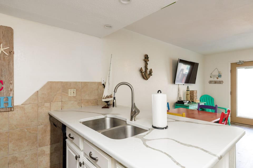 Your nautical-themed kitchen features elegant marble countertops, stainless steel sink, and charming coastal décor that makes meal prep feel like a seaside retreat.