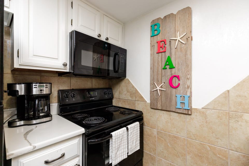 Cook your favorite meals in this fully equipped kitchen featuring modern appliances and charming beach-themed decor.