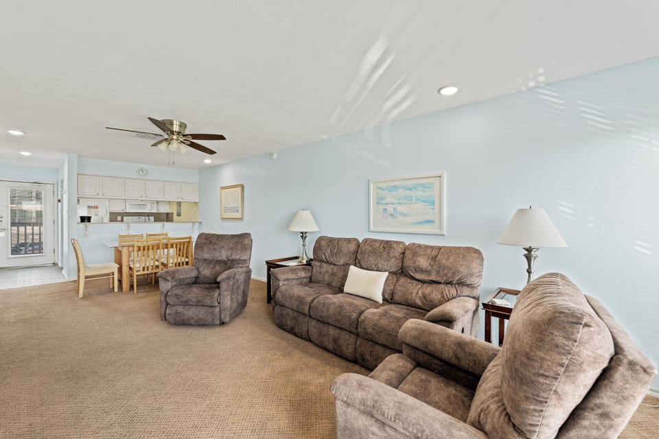 Stretch out in your spacious living area, where plush seating and coastal breezes from the ceiling fan invite you to unwind. Gather around the dining table for meals, laughter, and vacation memories.
