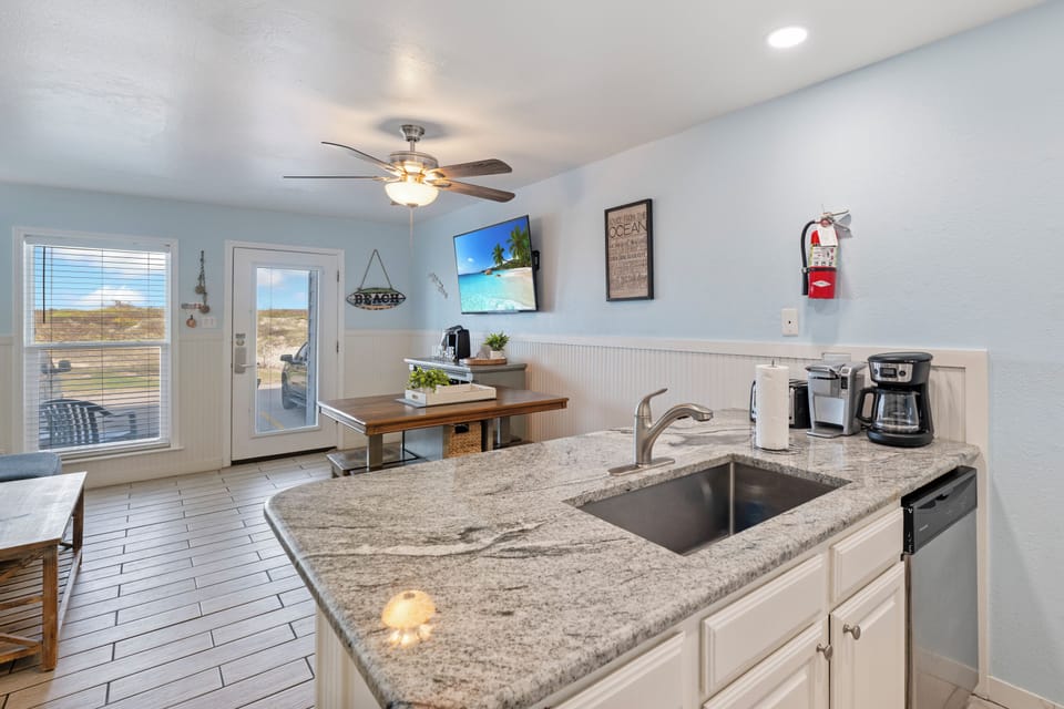 Your granite-topped kitchen island becomes the heart of your stay, with coffee brewing station ready for mornings overlooking coastal views.