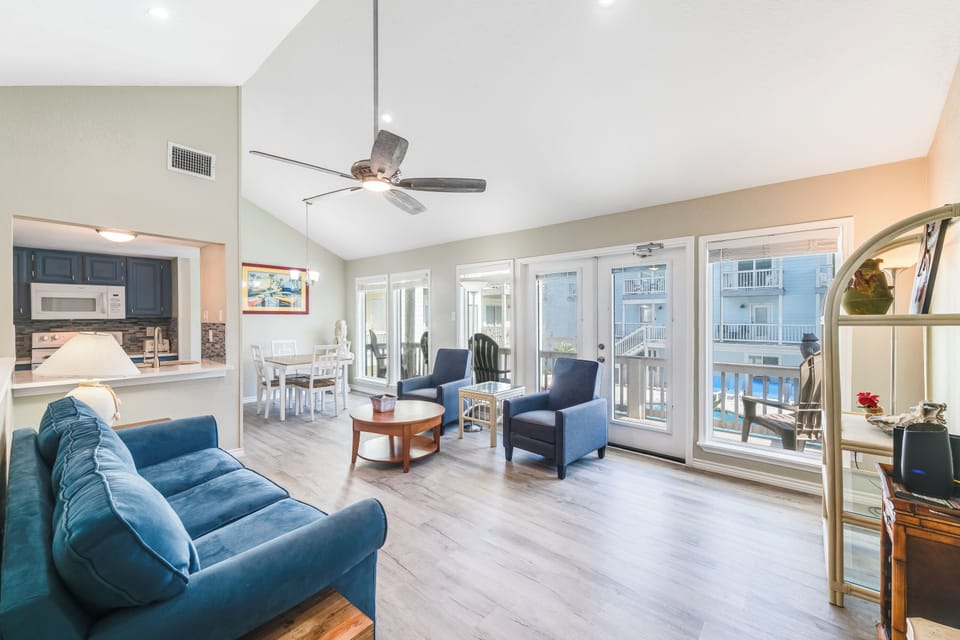 Relax in your spacious living room with plush blue seating and stunning balcony views of the surrounding buildings.