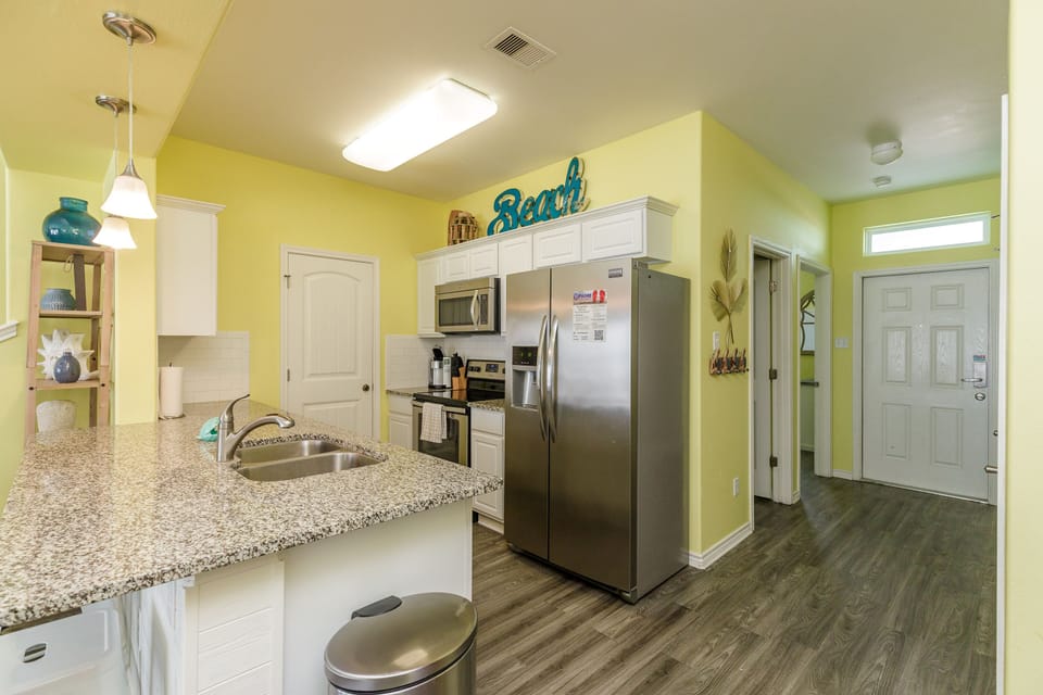 Your bright, fully-equipped kitchen awaits with granite countertops, stainless appliances, and cheerful yellow walls that make meal prep feel like vacation.