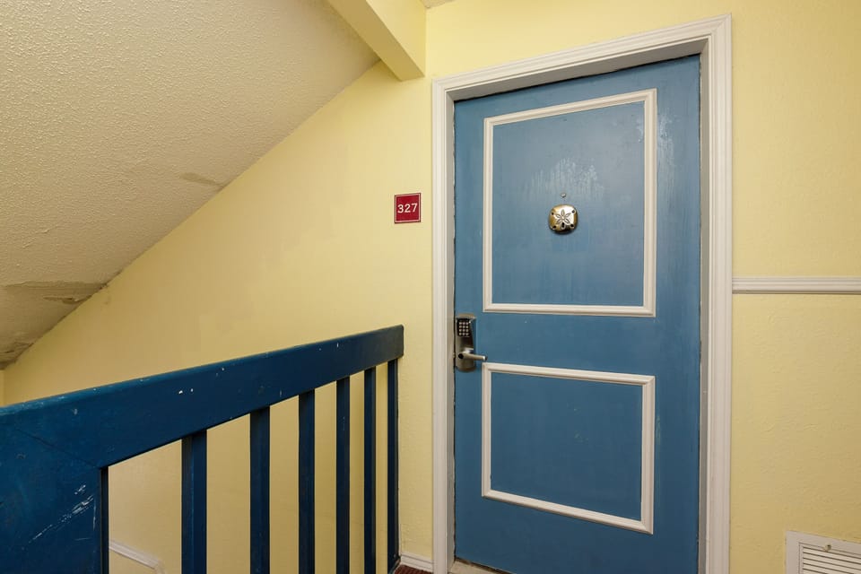 Your charming blue door welcomes you to room 327, perfectly positioned along the cozy stairway with its cheerful yellow walls.