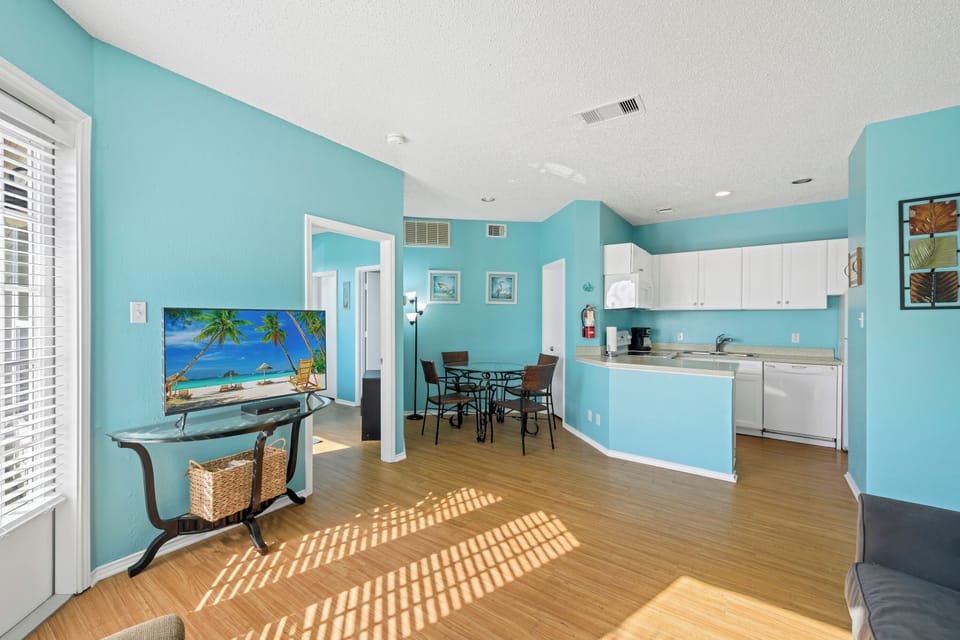 Unwind in your bright, tropical-inspired living space where turquoise walls and warm sunlight create the perfect beach getaway atmosphere.