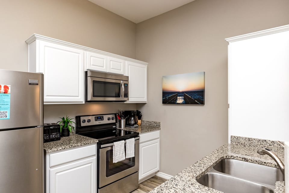 Cook your favorite meals in this bright, fully equipped kitchen featuring granite countertops, stainless appliances, and crisp white cabinetry.