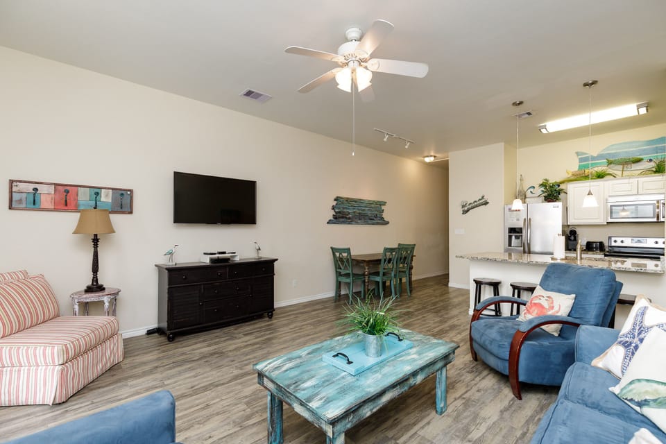 Relax in your spacious living room with coastal charm, complete with comfortable seating and modern amenities for the perfect beach getaway.