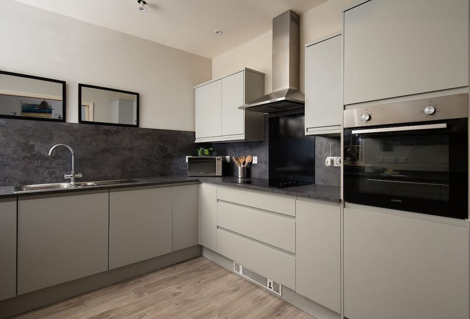 Farm Cottage - The kitchen features sleek grey cabinetry, its smooth surfaces reflecting soft light, while subtle details add a touch of modern elegance.