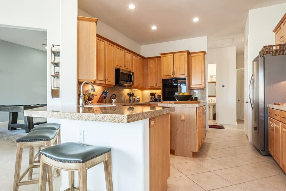 Where style meets function—this inviting kitchen boasts rich wood cabinetry, gleaming countertops, and a welcoming breakfast bar perfect for conversation and culinary creativity.