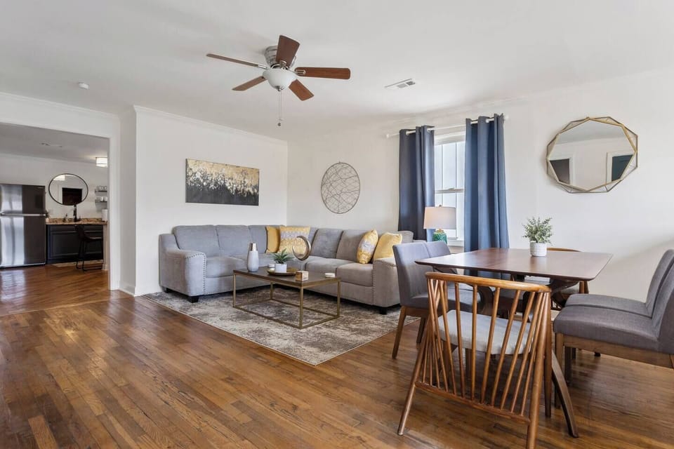 Front Living Room with Sectional Sofa, 65" Smart TV, and Dining Table.