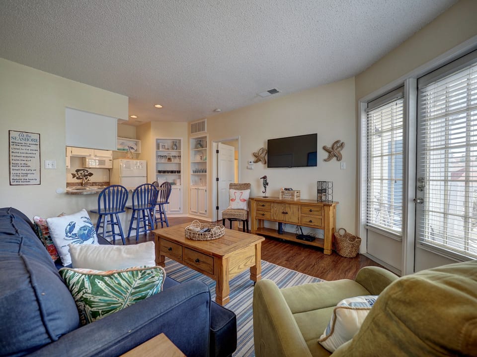 Relax in your coastal-themed living space with comfortable seating, nautical touches, and an open kitchen perfect for family meals.