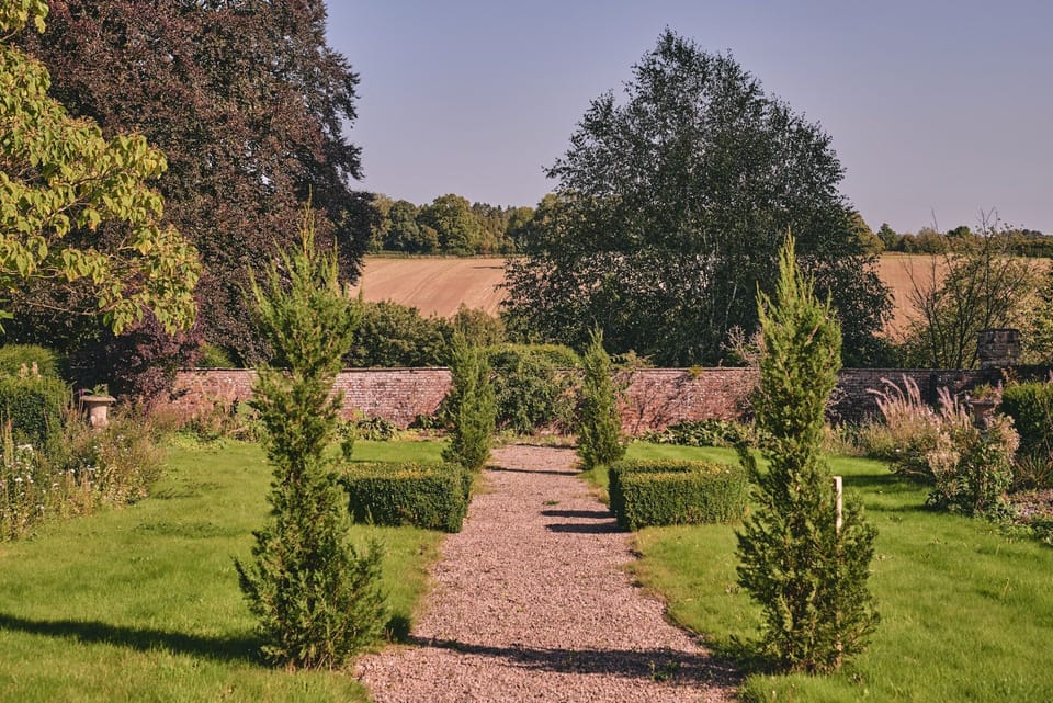 A cobbled pathway through the garden overlooking the countryside at Flock Cottage, Welsh Borders