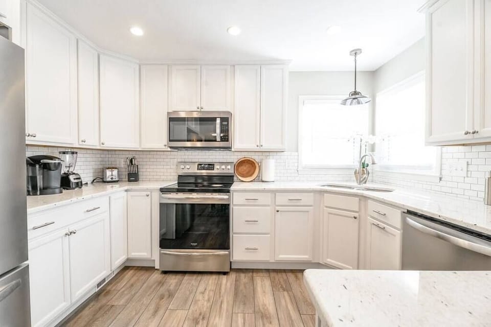Bright and spacious kitchen with a modern design, big windows, and a clean white backdrop. Perfectly equipped and filled with natural light for a refreshing cooking and dining experience.