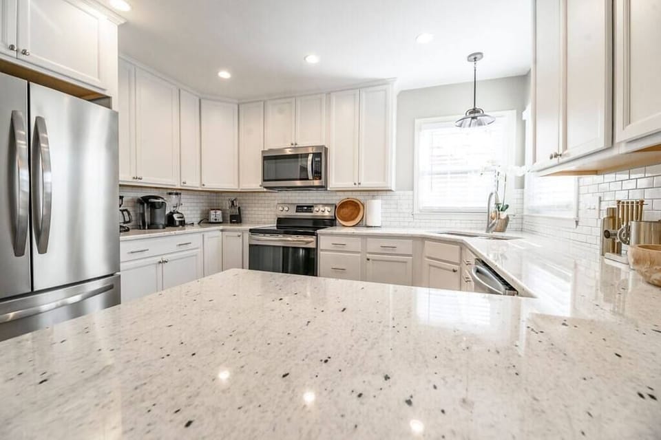 Elegant modern kitchen with crisp white cabinetry, stainless steel appliances, and quartz countertops, fully equipped for all your culinary needs.