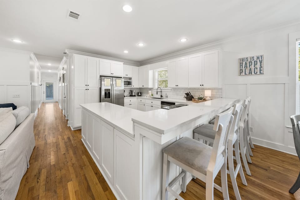Your spacious kitchen features pristine white cabinets, gleaming countertops, and modern appliances perfect for preparing memorable meals during your stay.
